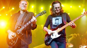 Rush Are Pleasantly Surprised When This Famous Superfan Crashes The Stage During Performance Of YYZ