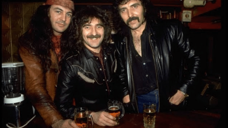 Ian Gillan, Geezer Butler, and Tony Iommi of Black Sabbath posing together with drinks in a bar setting.