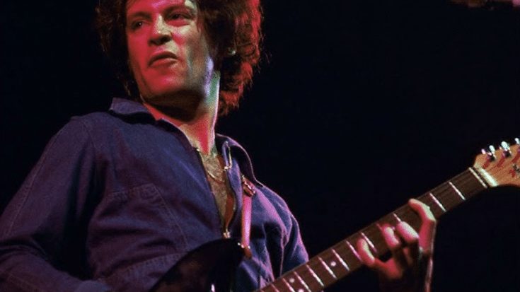 Eric Carmen performing live on stage with a guitar during a concert.