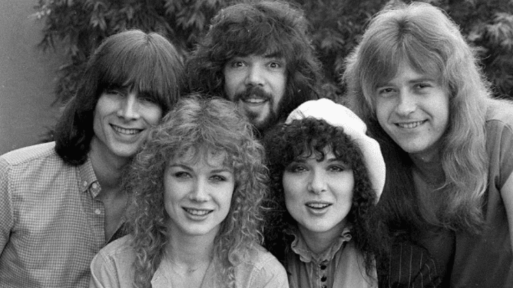 Heart in 1980, featuring Ann and Nancy Wilson along with band members, smiling together in a black-and-white setting.