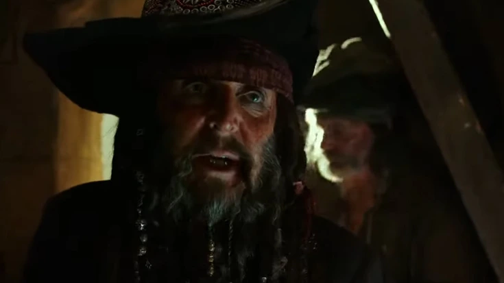 Paul McCartney dressed as a pirate in Pirates of the Caribbean: Dead Men Tell No Tales, appearing in a dimly lit prison cell scene.