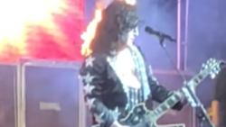 Kiss tribute band guitarist performing live in front of amplifiers as pyrotechnics erupt behind him on stage