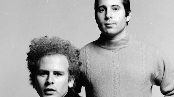 Simon and Garfunkel portrait from the 1960s, featuring Art Garfunkel with curly hair and Paul Simon in a knit sweater against a plain background.