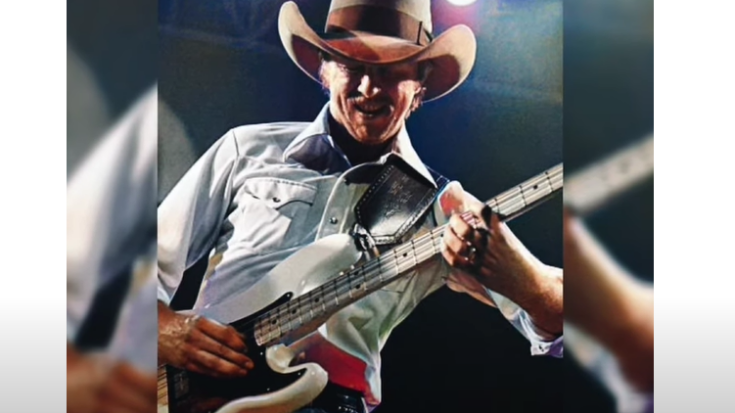 Tommy Caldwell playing bass guitar with the Marshall Tucker Band on stage under bright lights