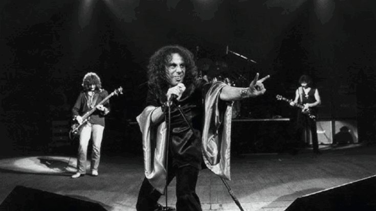 Ronnie James Dio commanding the stage with iconic metal horns gesture during a powerful live heavy metal performance
