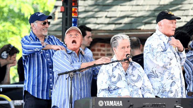 The Beach Boys performing live during their 50th anniversary reunion tour, with Brian Wilson at the keyboard and other band members on stage.