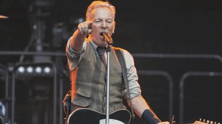 Bruce Springsteen passionately performing live on stage with electric guitar while pointing towards the crowd