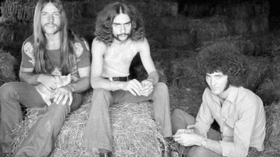 Grand Funk Railroad members sitting on hay bales during the early 1970s, showcasing their classic rock style and laid-back attitude.