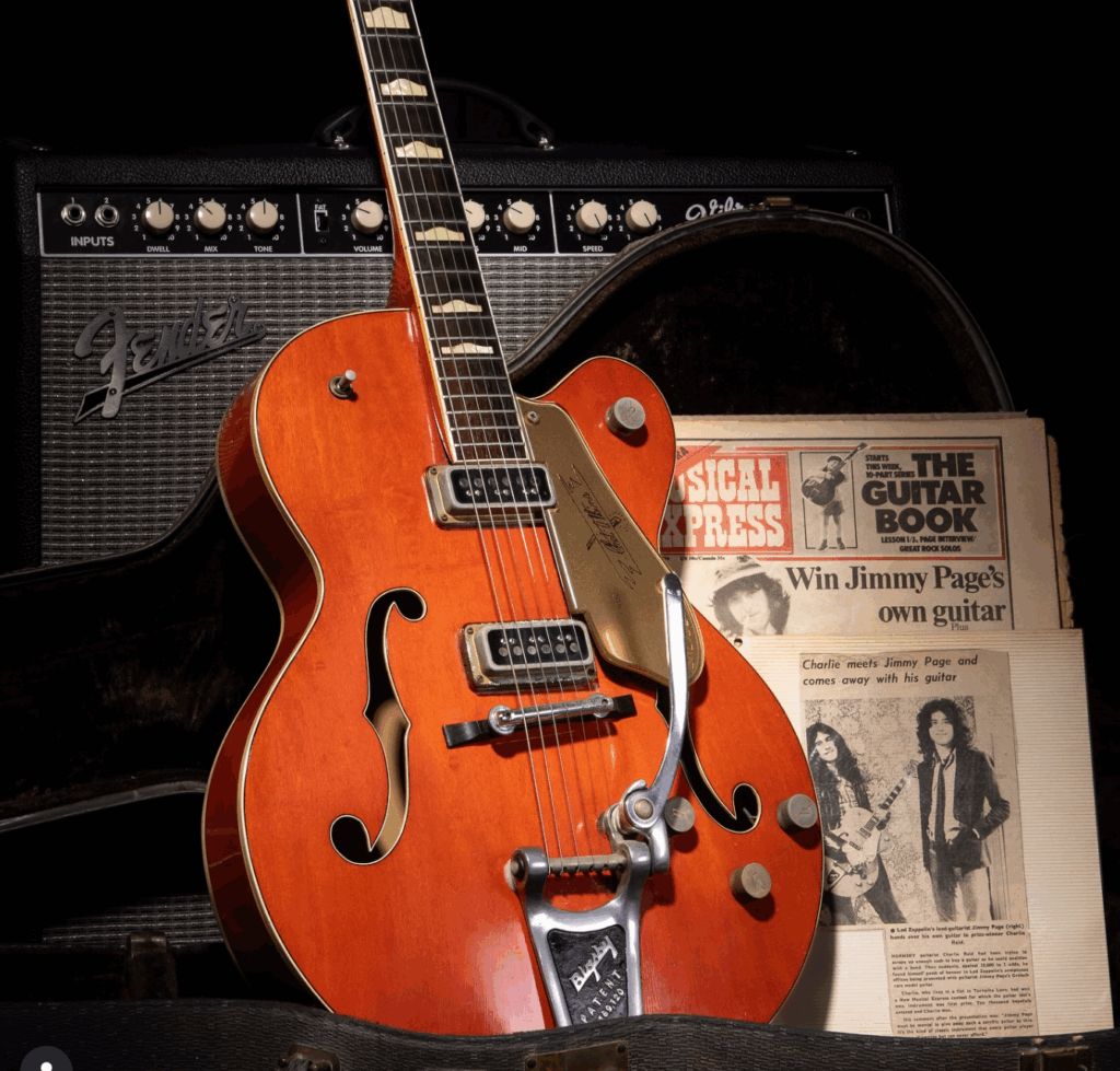 1957 Gretsch Chet Atkins 6120 guitar once owned by Jimmy Page, displayed with its case, a Fender amplifier, and original 1974 press materials from the New Musical Express giveaway competition
