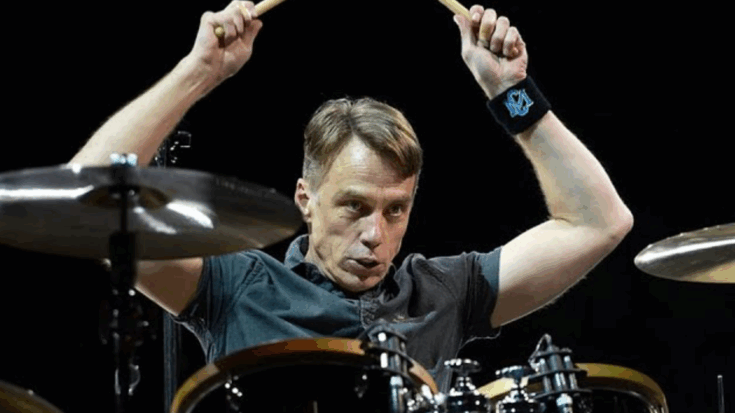 Matt Cameron in mid-performance raising drumsticks behind the kit during a live rock concert