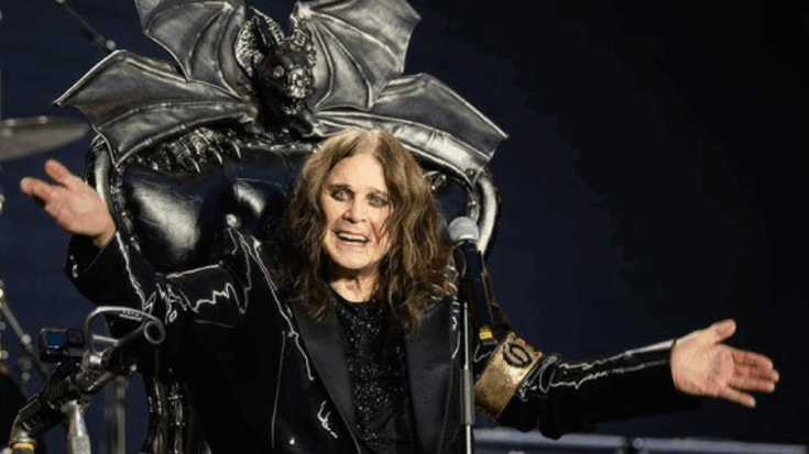 Ozzy Osbourne performing on stage seated on a gothic throne with bat wings, arms outstretched