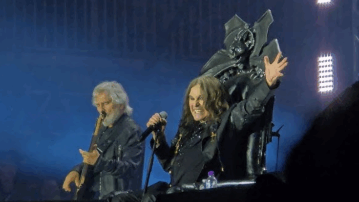 Ozzy Osbourne performing live on stage seated on a bat throne with a guitarist playing beside him