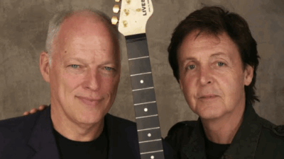 Paul McCartney and David Gilmour standing side by side with a guitar neck between them