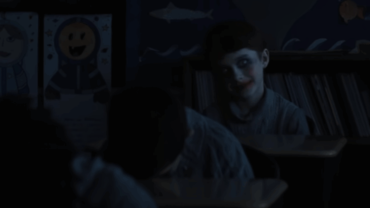 a boy with a sinister smile in a classroom