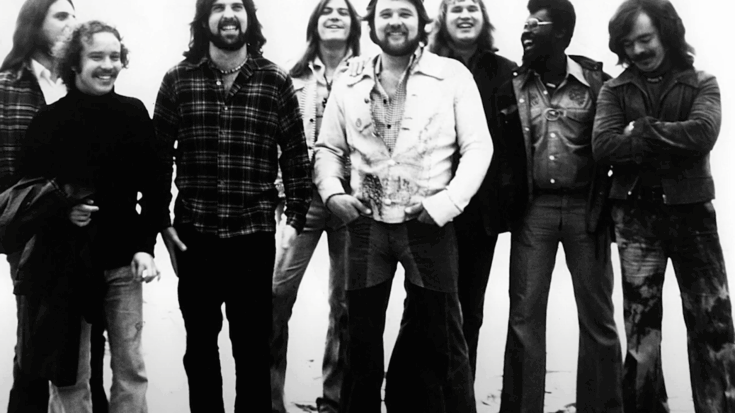Blood, Sweat & Tears standing together on a beach, smiling and laughing, dressed in casual 1970s clothing.
