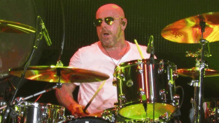 Jason Bonham playing drums on stage wearing sunglasses and a white shirt