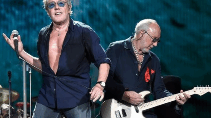 Roger Daltrey singing on stage while Pete Townshend plays guitar during a live performance.