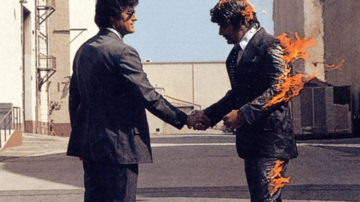 Two men in suits shaking hands, with one man on fire, from the Wish You Were Here album cover featuring stuntman Ronnie Rondell Jr.