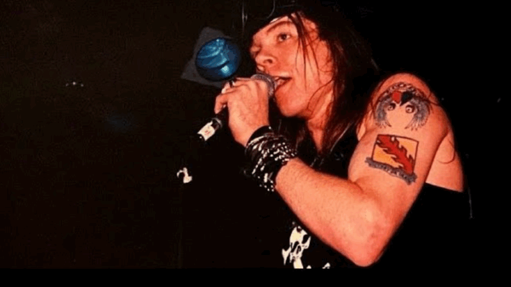 Axl Rose performing live on stage with microphone in hand during Guns N’ Roses concert.