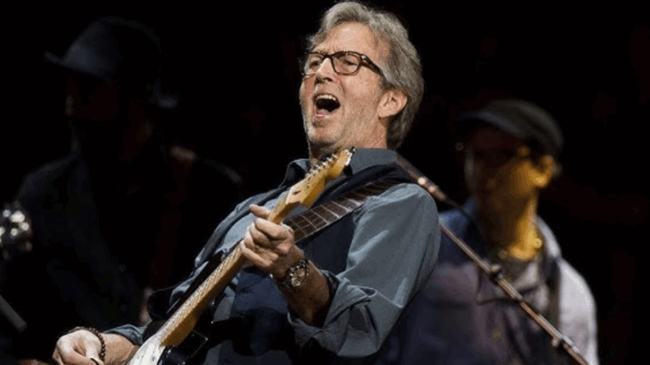 Eric Clapton playing guitar passionately on stage during a live performance.