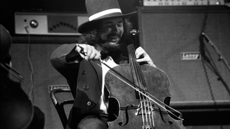 Mike Edwards of Electric Light Orchestra playing cello on stage in a top hat.