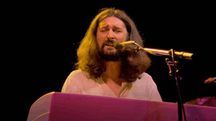 Rick Davies performing on stage while playing keyboard and singing into a microphone