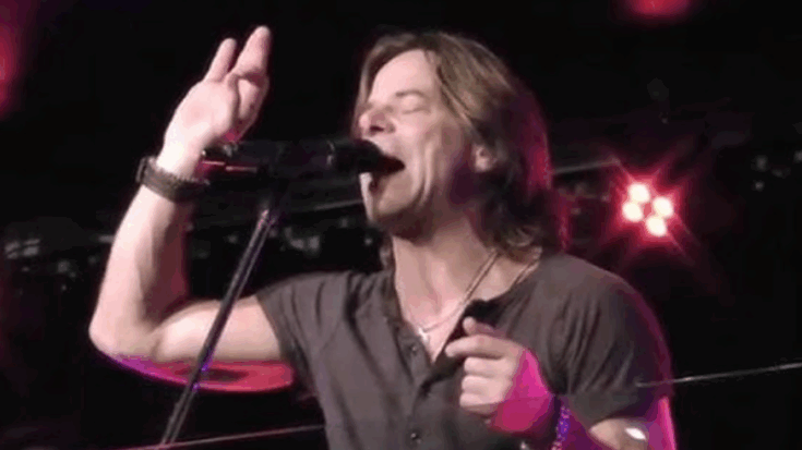 Rick Hughes delivering a powerful live performance on stage with passionate vocals.