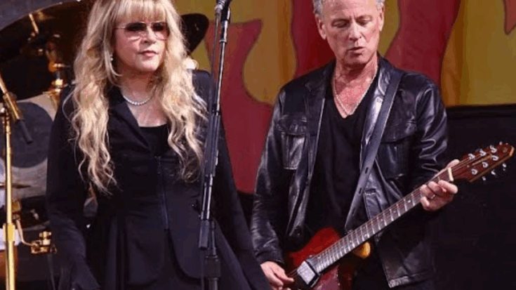 Stevie Nicks and Lindsey Buckingham performing together on stage, with Nicks singing into the microphone and Buckingham playing guitar.