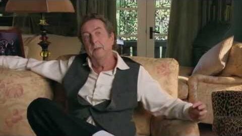 Eric Idle sitting on a sofa