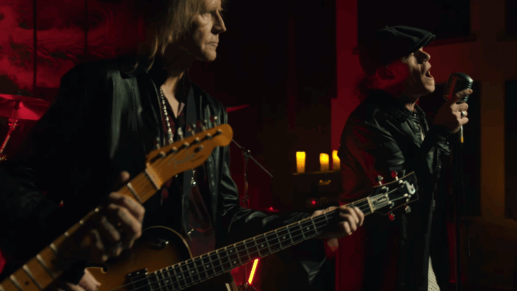 Close Enemies performing their song “More Than I Could Ever Need” with Aerosmith bassist Tom Hamilton playing bass alongside the lead singer under red stage lighting.