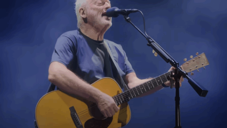 David Gilmour performing “Wish You Were Here” live at the Circus Maximus, playing acoustic guitar under blue stage lighting.
