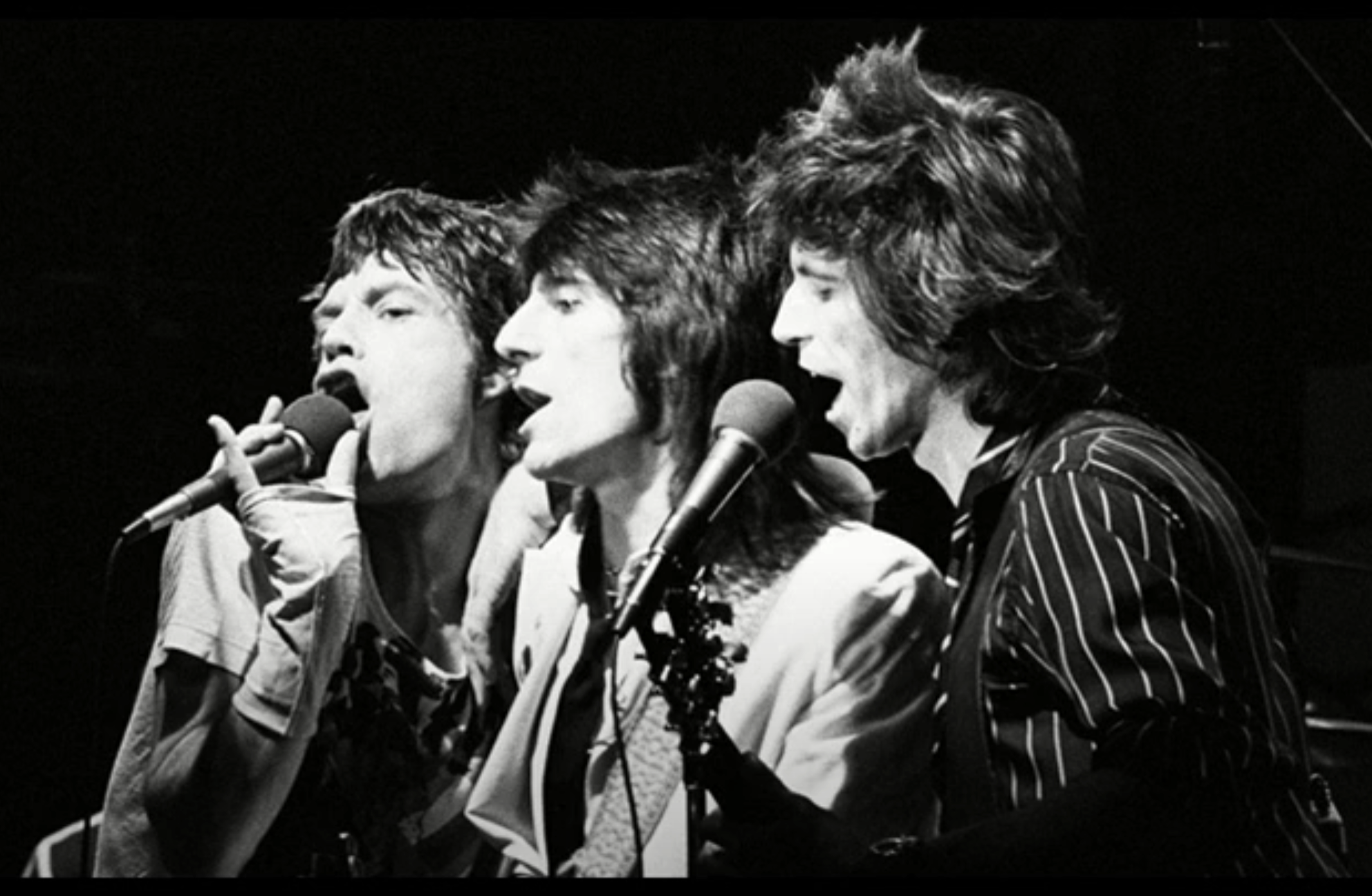 The Rolling Stones performing together on stage, singing into microphones during their 1978 “Beast of Burden” appearance on Saturday Night Live.