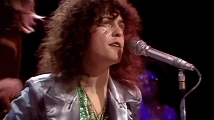 Marc Bolan of T. Rex performing “Get It On” on Top of the Pops in 1971 wearing a silver jacket and glitter detail under stage lights.
