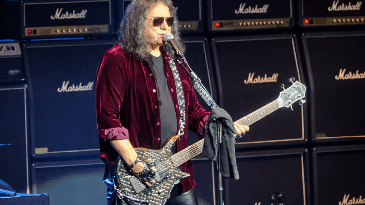 Gene Simmons performs onstage with his bass in front of a wall of Marshall amps.