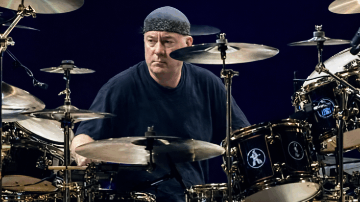 Neil Peart plays his drum kit with focused intensity during a live performance.