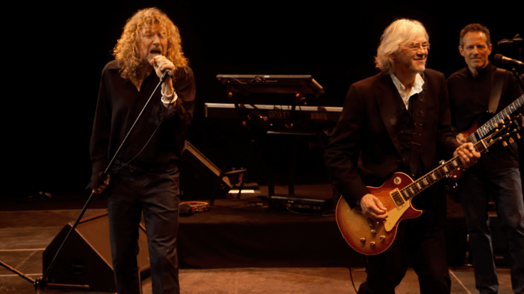 Robert Plant sings at center stage while Jimmy Page plays guitar beside him during a live performance.