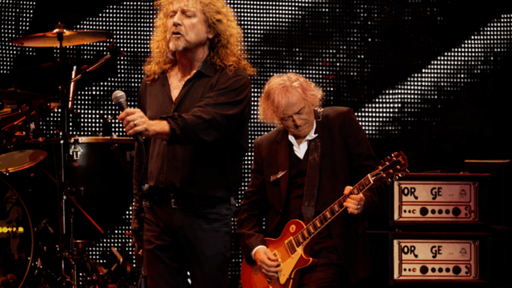 Robert Plant holds the microphone while Jimmy Page plays guitar beside him onstage.