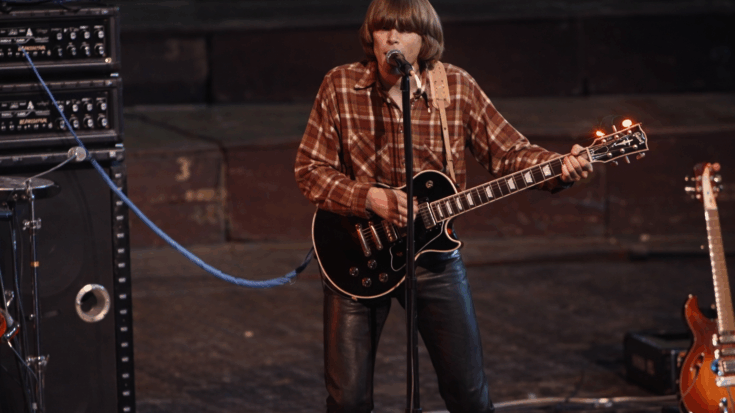 John Fogerty delivers a powerful performance, singing and playing his guitar.