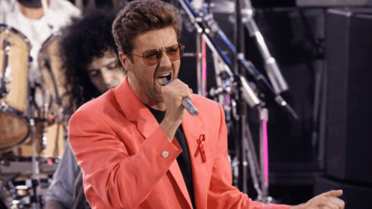 George Michael delivers a powerful live performance, singing passionately into the microphone in a bright coral jacket.