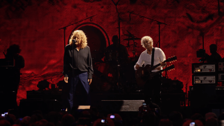 Led Zeppelin commands the stage as Robert Plant sings beside Jimmy Page under a blazing red backdrop.