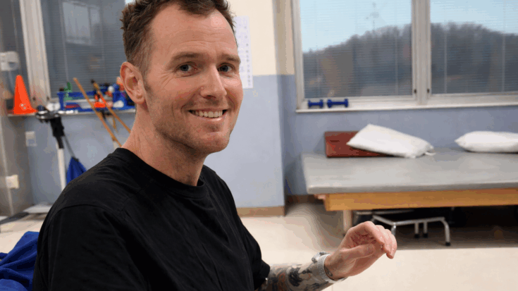 Chad Gilbert smiles warmly while sitting in a rehab room in a relaxed moment.