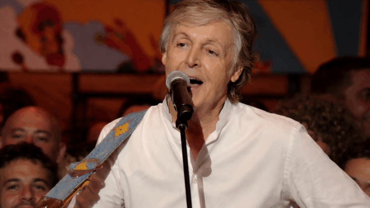 Paul McCartney sings into a microphone during a warm, intimate live performance.