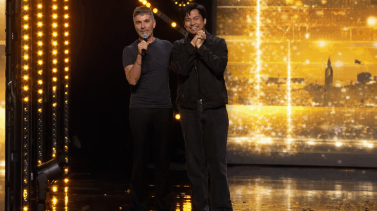 Matty Juniosa and Simon stand side by side on a brightly lit stage, smiling as one holds a microphone.