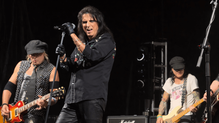 Alice Cooper grips the microphone with intensity as he delivers a powerful performance on stage.
