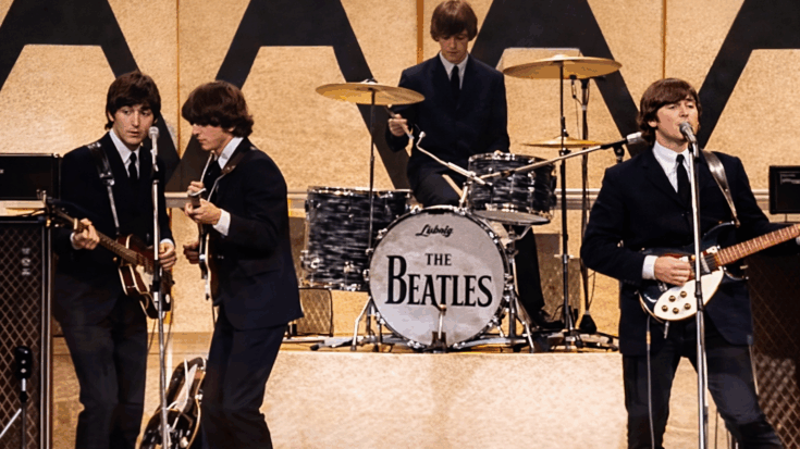 The Beatles perform on stage in matching suits, with guitars up front and Ringo Starr playing drums behind them.