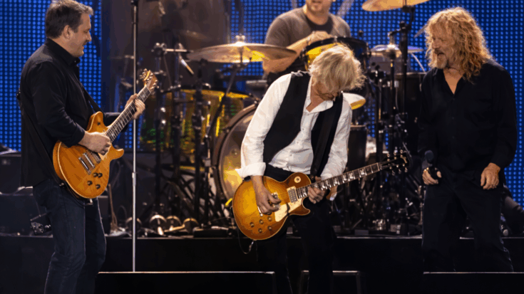 Led Zeppelin performs on stage with Jimmy Page playing guitar at center while the band rocks behind him.
