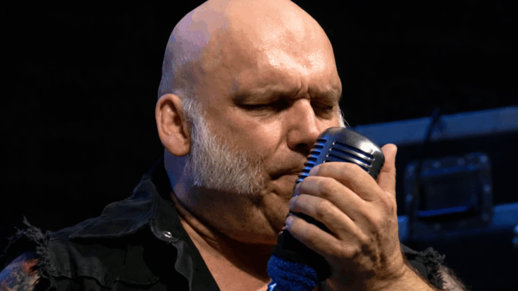 Blaze Bayley sings into a vintage-style microphone, eyes closed with intense focus during a live performance.