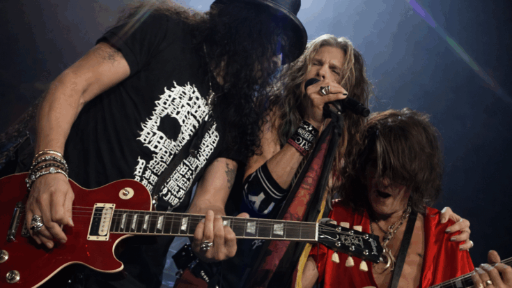 Aerosmith rocks the stage together in a tight live performance moment, with guitars up front and Steven Tyler singing at the center.