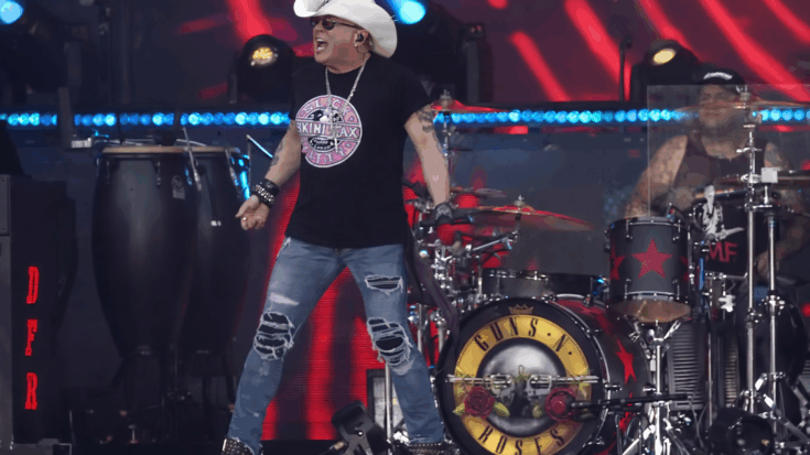 Guns N’ Roses light up the stage as Axl Rose performs in front of the band’s drum kit under vivid red and blue lights.