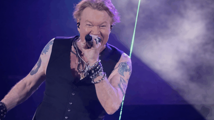Axl Rose leans into the spotlight, singing fiercely into the microphone with electric energy.